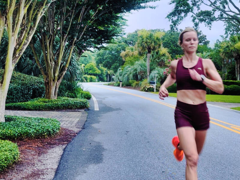 Whitney Heins running in red sports bra and red shorts.