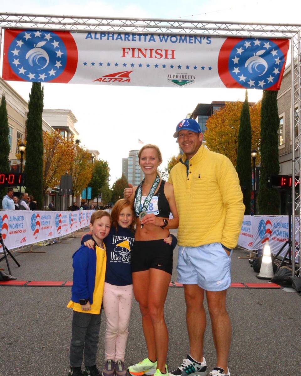 Whitney Heins with her family with a race medal around her neck at the finish.