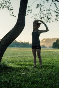 Runner stretching near tree