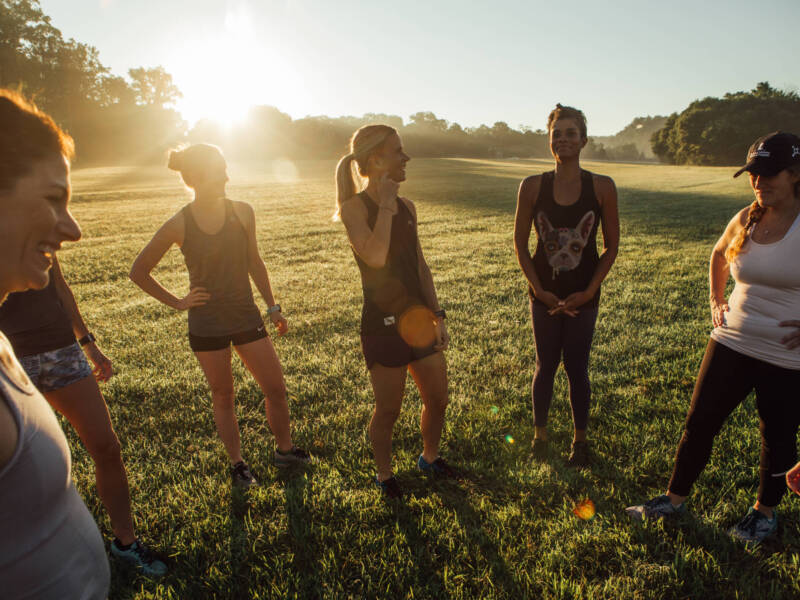 women in running clothes standing in a field at dawn