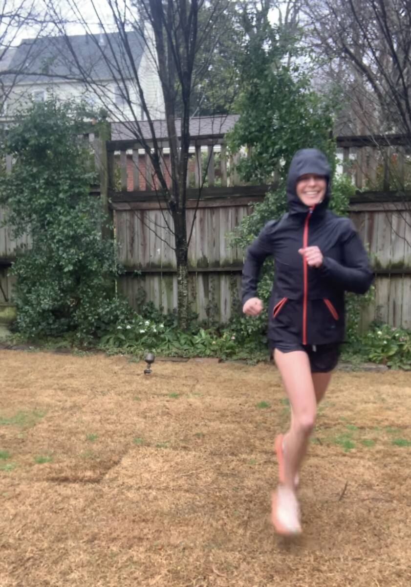 Whitney Heins running in black rain jacket