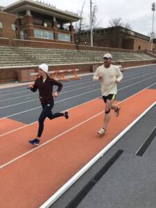 whitney and her husband running in cold weather gear on a track