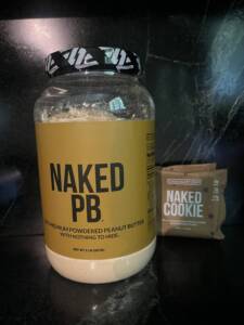 Naked Nutrition protein powder and cookie in package on counter.