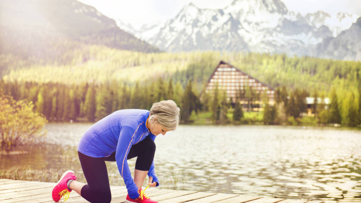 older lady tying running shoe in mountains