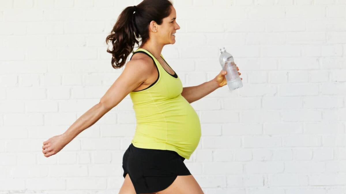 pregnant woman in yellow walking with water bottle