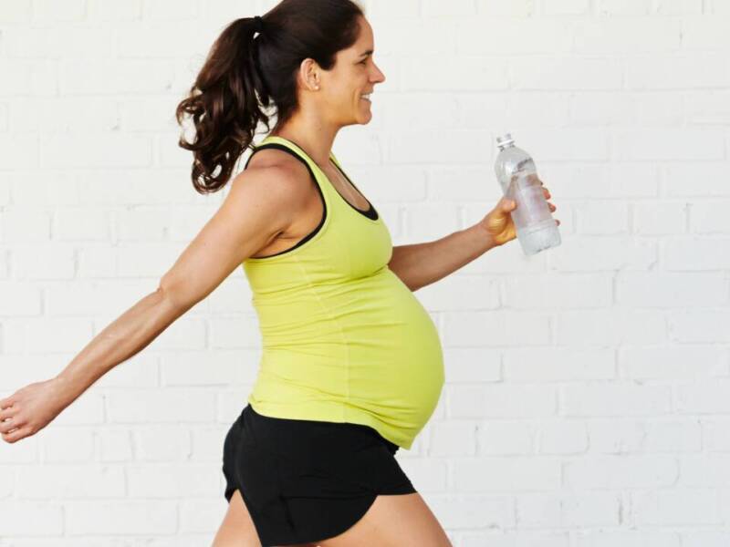 pregnant woman in yellow walking with water bottle