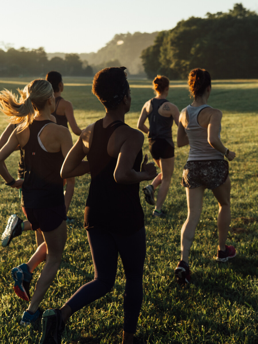 women running in a field at sunrise